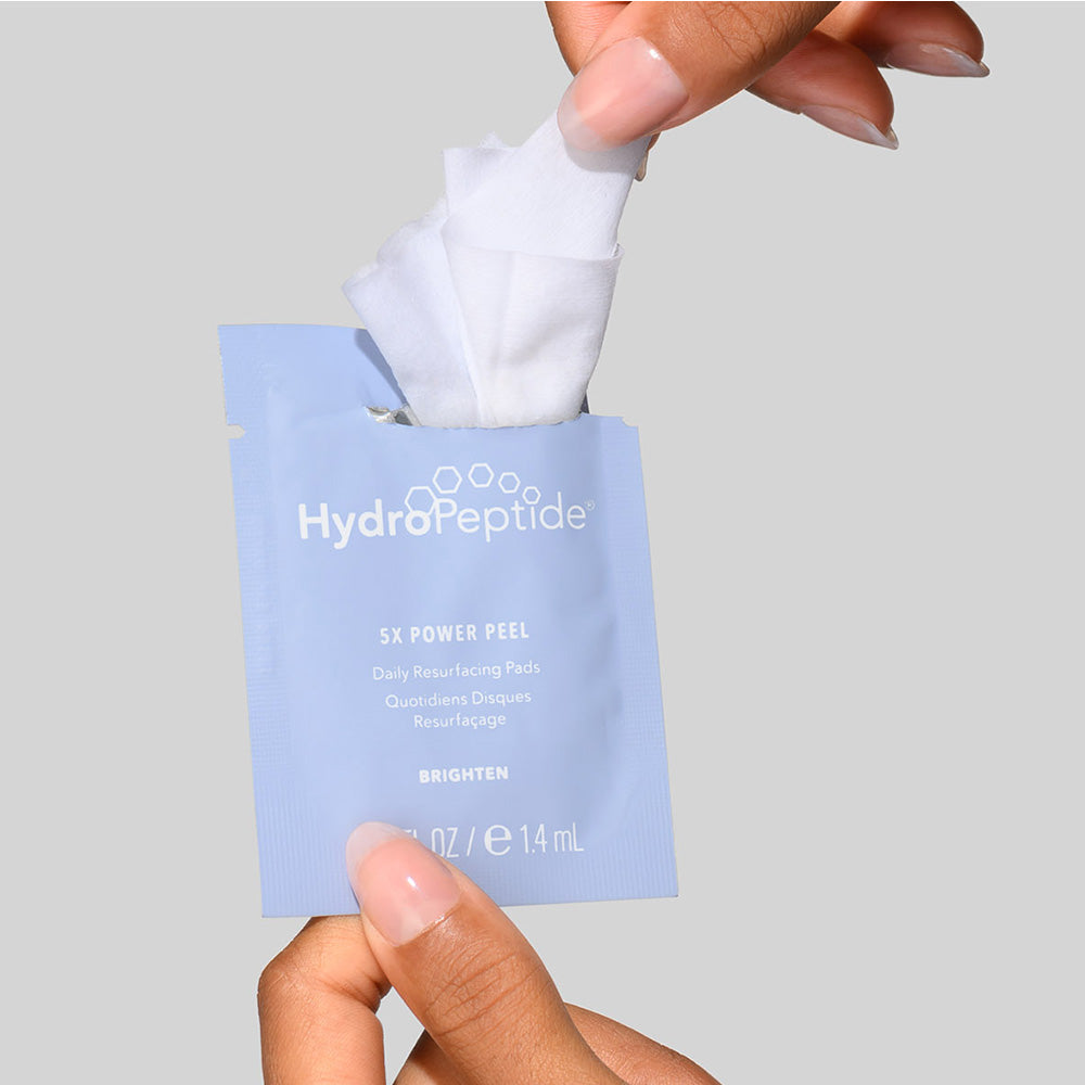 HydroPeptide 5X Power Peel packet held by a hand against a gray background